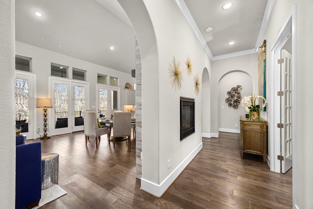 hallway with arched walkways, french doors, dark wood-style flooring, ornamental molding, and baseboards