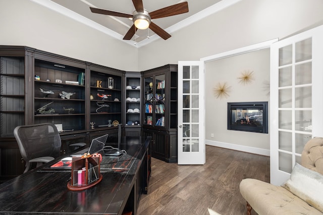 office space featuring dark wood-style floors, french doors, ornamental molding, a glass covered fireplace, and a ceiling fan