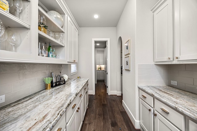 bar featuring white cabinetry, light stone countertops, dark hardwood / wood-style floors, and backsplash