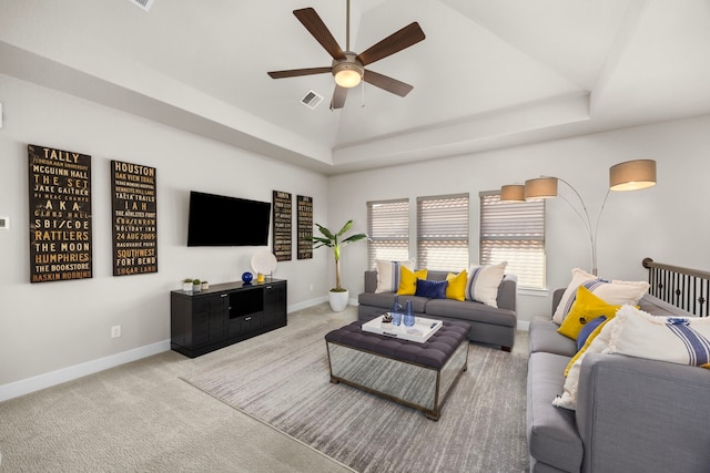 living room featuring light carpet, ceiling fan, and a tray ceiling