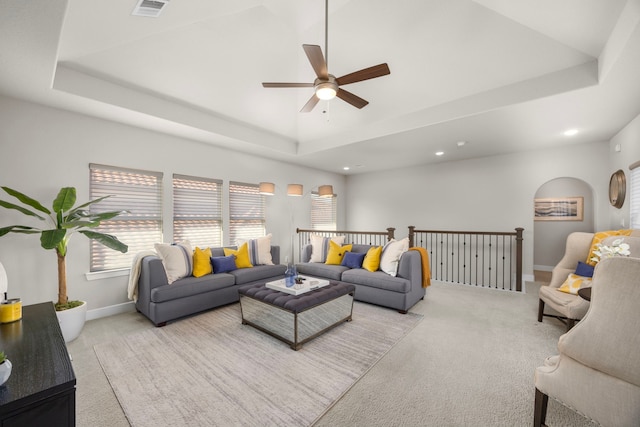 living room featuring ceiling fan, light colored carpet, and a raised ceiling