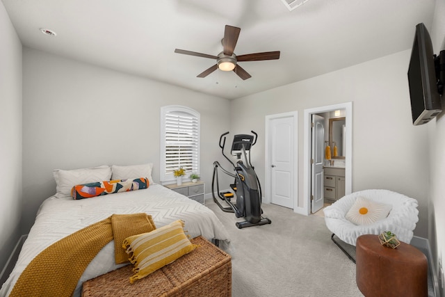 bedroom with baseboards, light colored carpet, ceiling fan, and ensuite bath