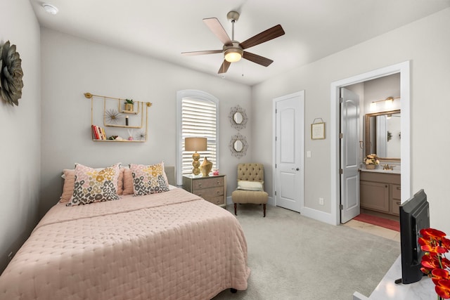 bedroom with light carpet, ceiling fan, baseboards, and ensuite bathroom