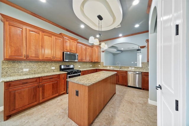 kitchen with sink, crown molding, appliances with stainless steel finishes, a kitchen island, and a raised ceiling