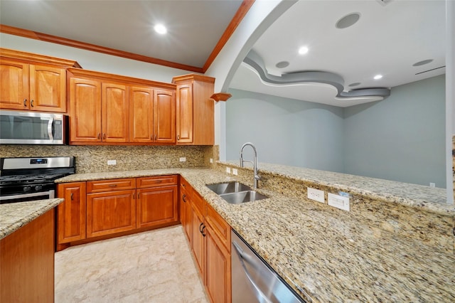 kitchen with ornamental molding, appliances with stainless steel finishes, light stone countertops, and sink