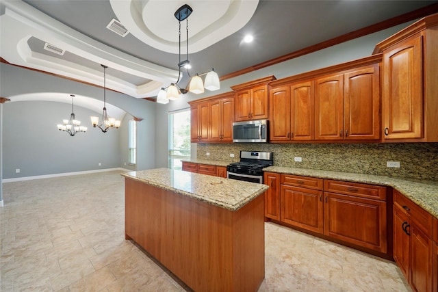 kitchen with appliances with stainless steel finishes, hanging light fixtures, a center island, light stone counters, and a raised ceiling