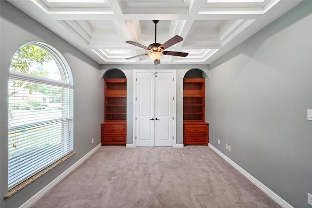 unfurnished bedroom with ceiling fan, coffered ceiling, light carpet, and beam ceiling