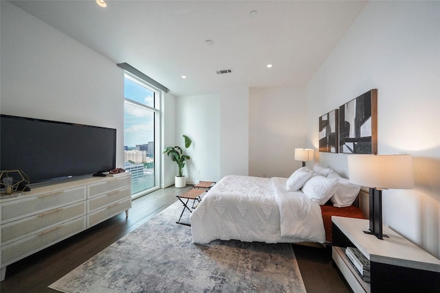 bedroom with expansive windows, dark hardwood / wood-style floors, and access to outside