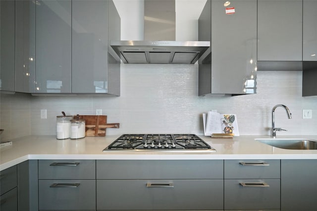 kitchen featuring sink, gray cabinets, tasteful backsplash, and wall chimney range hood