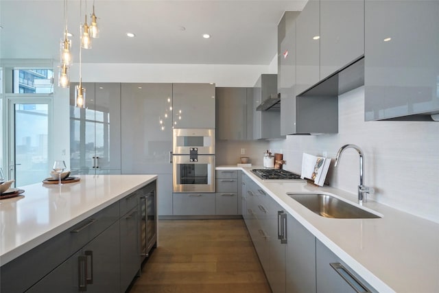 kitchen featuring appliances with stainless steel finishes, gray cabinetry, sink, pendant lighting, and dark hardwood / wood-style floors