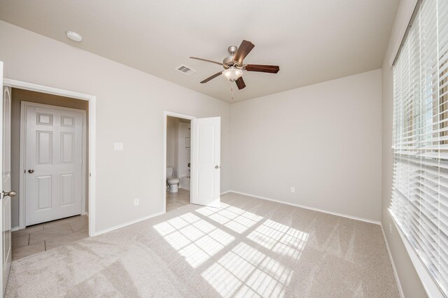 unfurnished bedroom with ceiling fan, light colored carpet, and ensuite bath