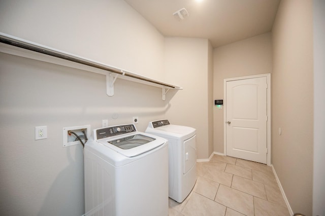 washroom with light tile patterned floors and washing machine and dryer