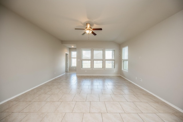 empty room with ceiling fan, vaulted ceiling, and light tile patterned flooring