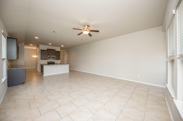 unfurnished living room featuring light tile patterned floors and ceiling fan