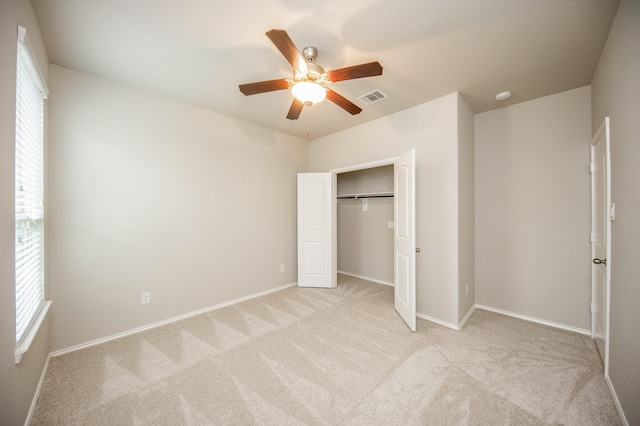 unfurnished bedroom featuring ceiling fan, light colored carpet, and a closet