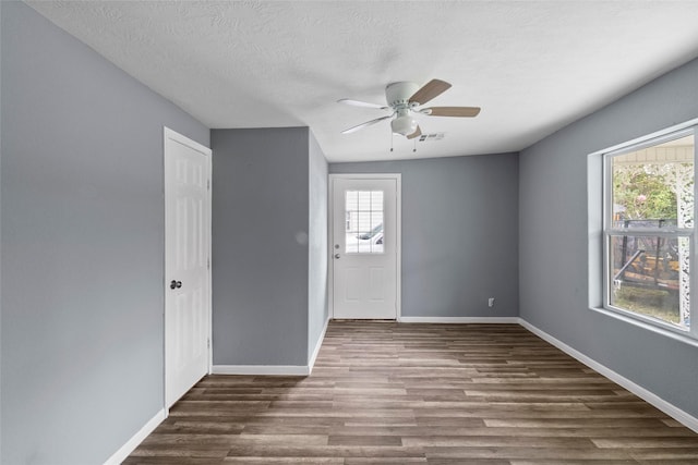 unfurnished room featuring ceiling fan, dark wood-type flooring, and a textured ceiling