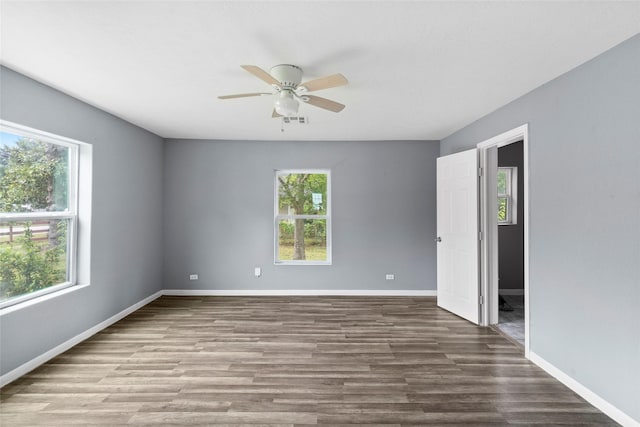 spare room with ceiling fan, plenty of natural light, and wood-type flooring