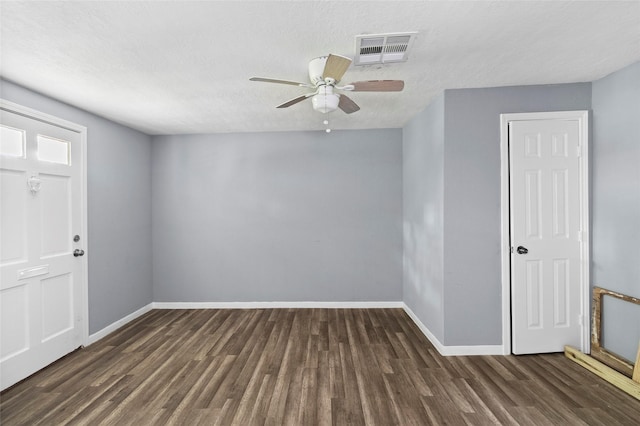 spare room featuring ceiling fan, dark wood-type flooring, and a textured ceiling