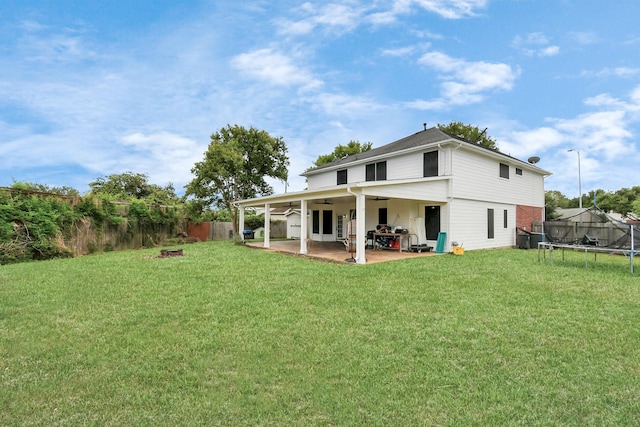 back of property featuring a lawn, a patio, ceiling fan, and a trampoline