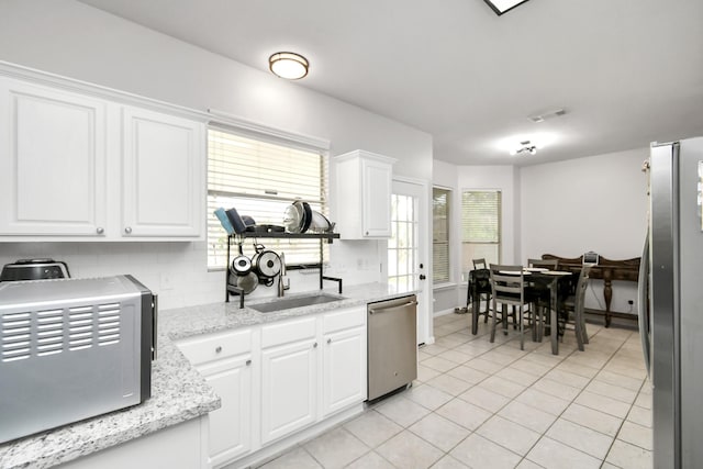 kitchen featuring light stone counters, light tile patterned flooring, white cabinets, and appliances with stainless steel finishes