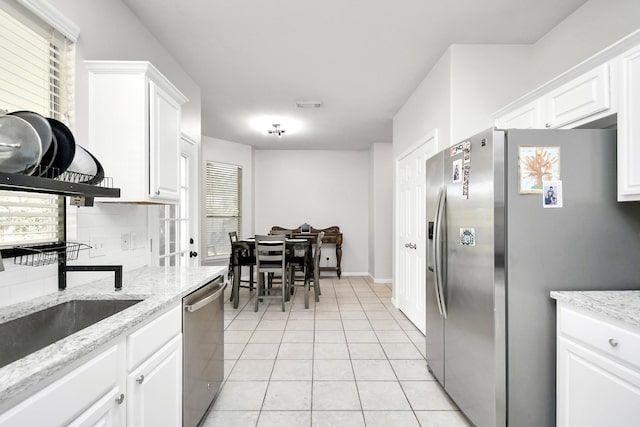 kitchen featuring sink, white cabinets, light stone counters, light tile patterned flooring, and stainless steel appliances