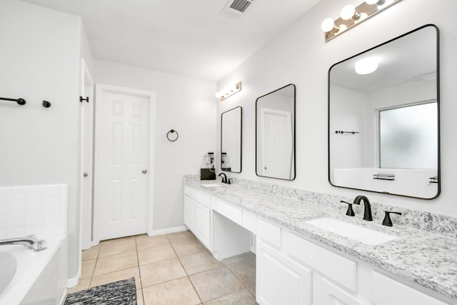 bathroom featuring tile patterned flooring, tiled bath, and vanity