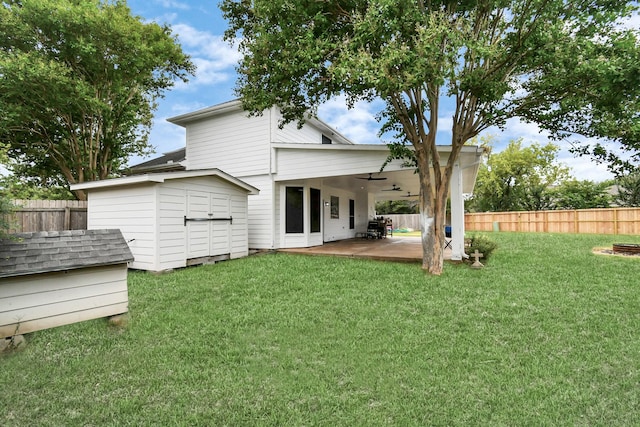 back of house with ceiling fan, a patio area, a shed, and a yard