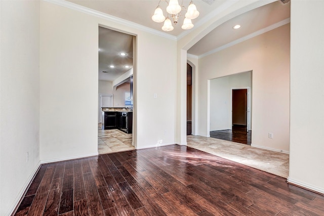 spare room with hardwood / wood-style flooring, a notable chandelier, and ornamental molding