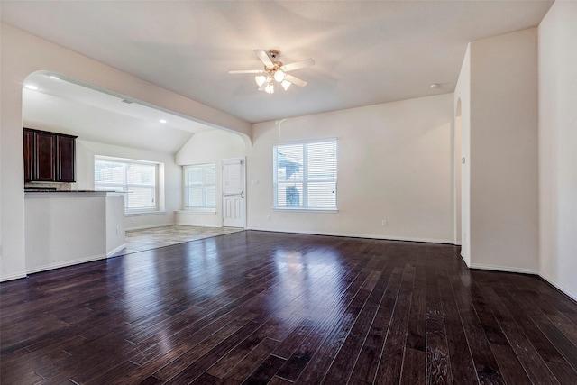 unfurnished living room featuring ceiling fan, dark wood-type flooring, and lofted ceiling with beams