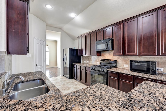 kitchen featuring black appliances, dark stone counters, sink, and lofted ceiling