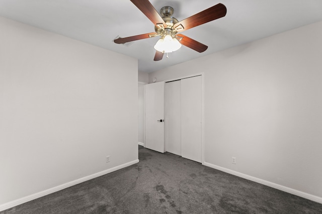 unfurnished bedroom featuring dark colored carpet, a closet, and ceiling fan