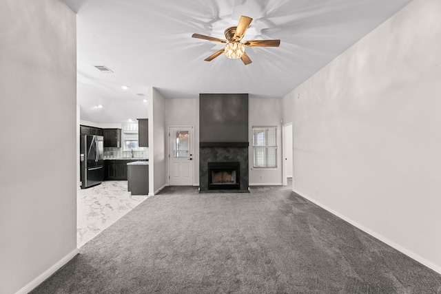 unfurnished living room with ceiling fan, light colored carpet, and a fireplace