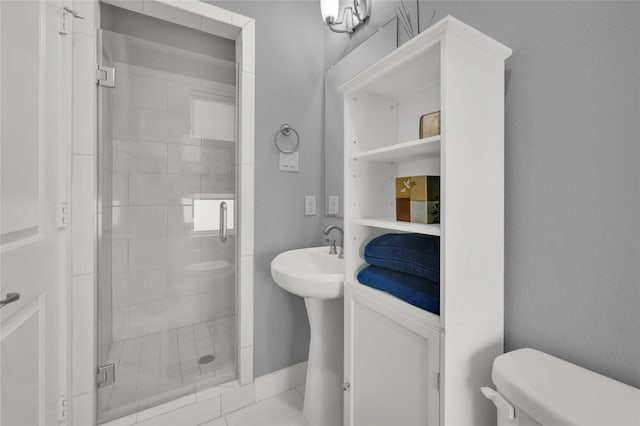 bathroom with a shower with door, sink, tile patterned floors, and toilet