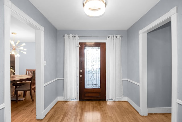 foyer with light wood-type flooring and an inviting chandelier