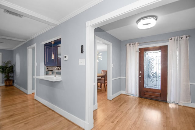 foyer featuring sink, light hardwood / wood-style flooring, and ornamental molding