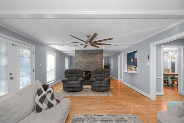 living room featuring ceiling fan, wood-type flooring, ornamental molding, and a stone fireplace