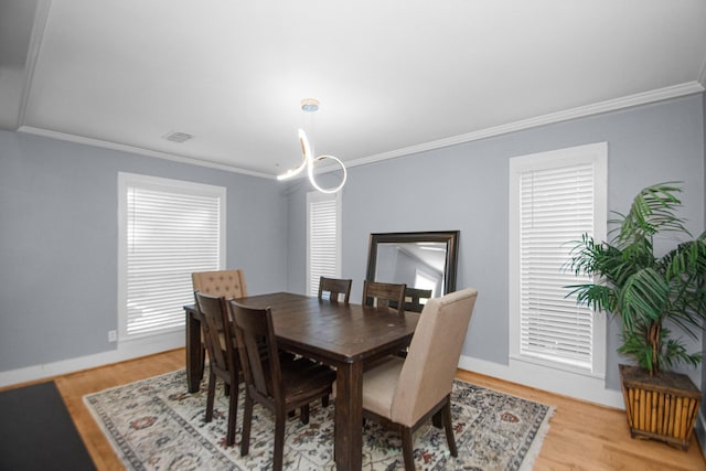 dining space featuring light hardwood / wood-style floors, a chandelier, and ornamental molding