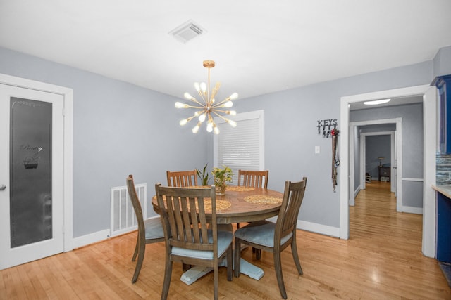 dining space with light hardwood / wood-style flooring and a notable chandelier