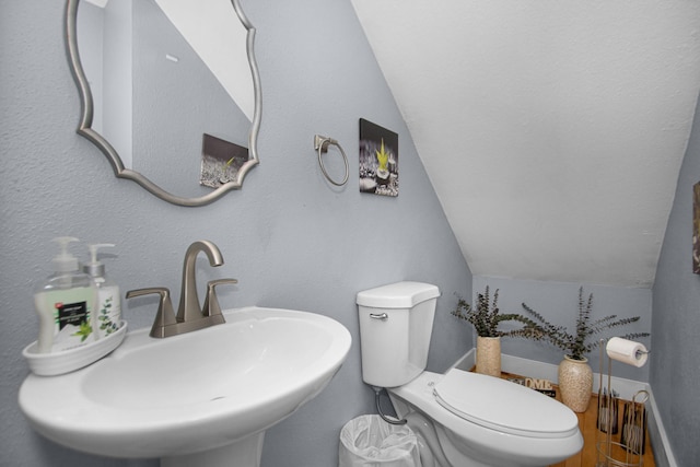 bathroom with sink, toilet, and lofted ceiling