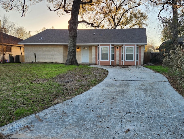 ranch-style house with a yard and central AC