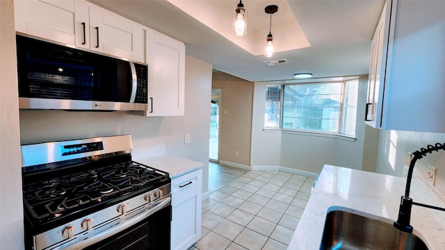 kitchen featuring hanging light fixtures, light tile patterned floors, stainless steel appliances, light stone countertops, and white cabinets