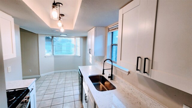 kitchen with stainless steel gas range, sink, white cabinetry, decorative light fixtures, and light stone countertops