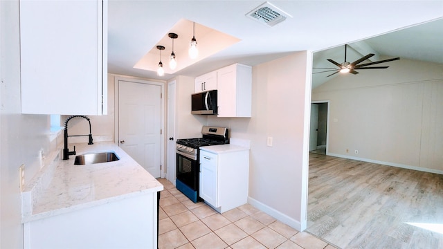 kitchen with sink, appliances with stainless steel finishes, hanging light fixtures, light stone countertops, and white cabinets