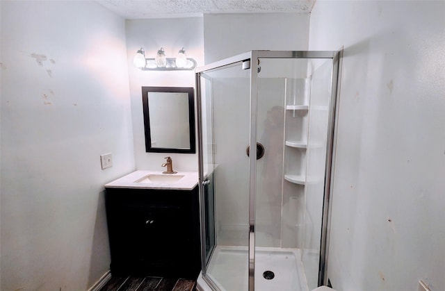 bathroom with vanity, an enclosed shower, and a textured ceiling