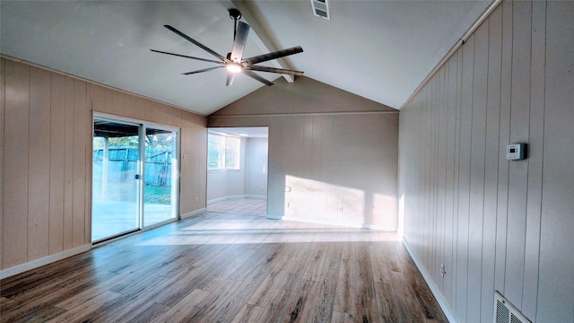 unfurnished room with hardwood / wood-style flooring, ceiling fan, wooden walls, and lofted ceiling with beams