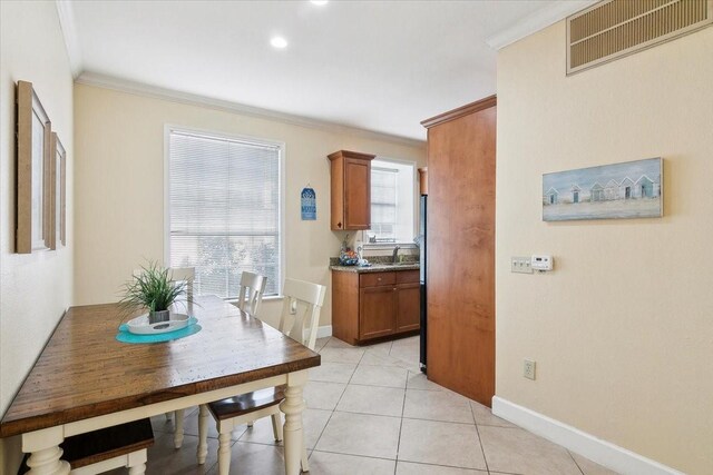 dining room featuring sink, light tile patterned floors, and ornamental molding