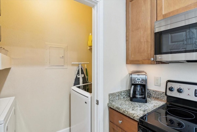 kitchen with light stone counters, appliances with stainless steel finishes, washer / dryer, and electric panel