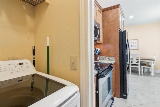 laundry room with washer / dryer and light tile patterned flooring