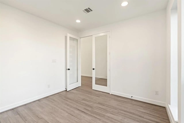 unfurnished bedroom with french doors and light hardwood / wood-style floors