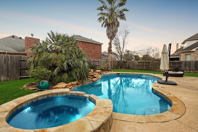 pool at dusk with an in ground hot tub